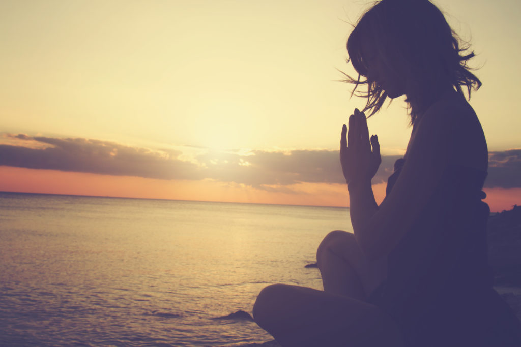 young woman practicing yoga on the beach