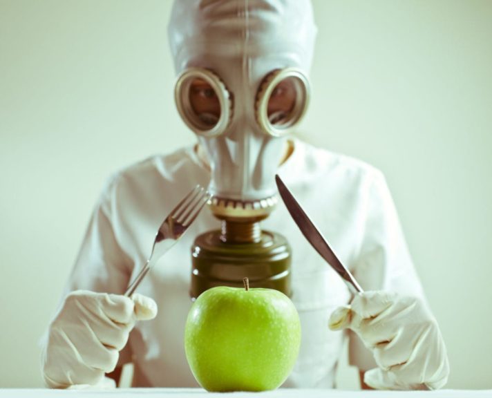 Person wearing gas mask, ready to eat an apple