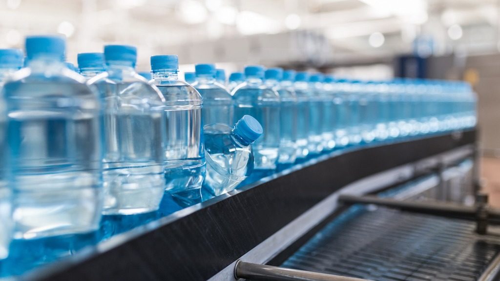 Botellas de agua distribuidas y fabricadas en una fábrica de agua para simbolizar la privatización del agua